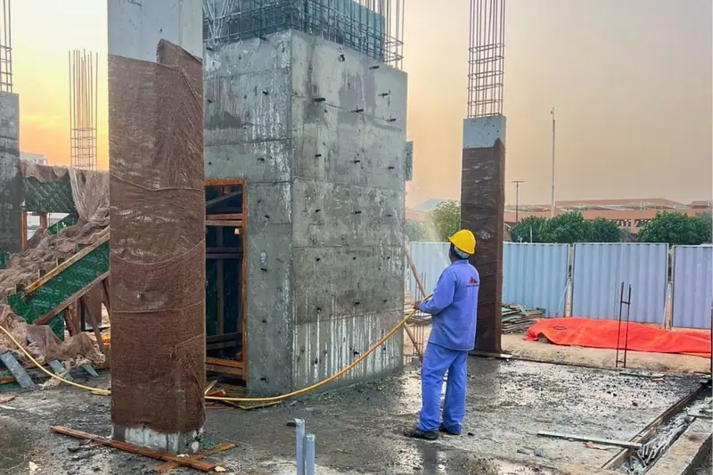 Worker curing concrete columns at a villa construction site, Sharjah